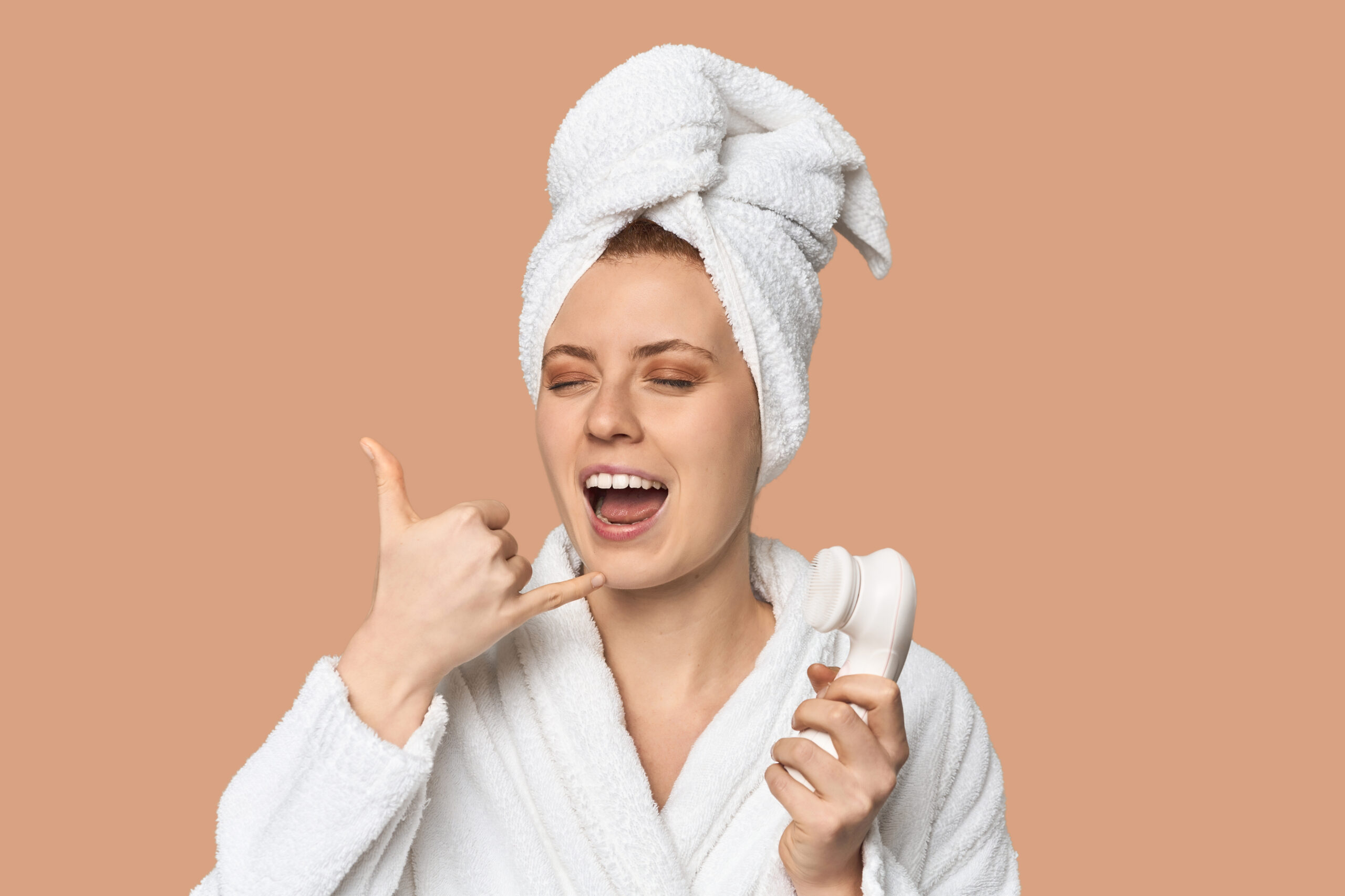 Young Caucasian redhead with facial device showing a mobile phone call gesture with fingers.