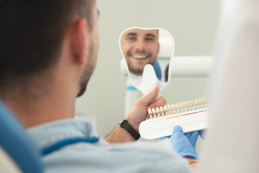 Handsome young man in stomatology clinic with female dentist. Healthy teeth whitening.